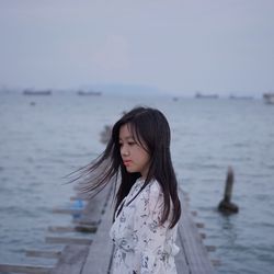 Beautiful woman standing by sea against sky