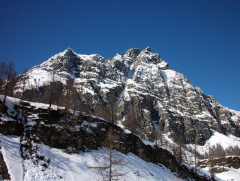 Low angle view of snowcapped mountain against clear blue sky