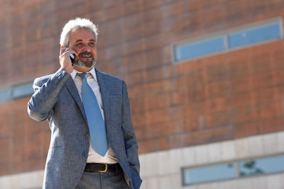 Mature man using mobile phone while standing outdoors