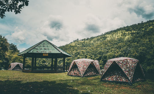 Camping by trees on field against sky