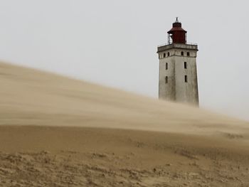 Lighthouse by sea against sky