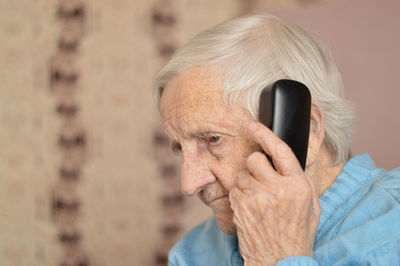 Close-up of a 90-year-old elderly retired woman who is talking anxiously the phone. selective focus