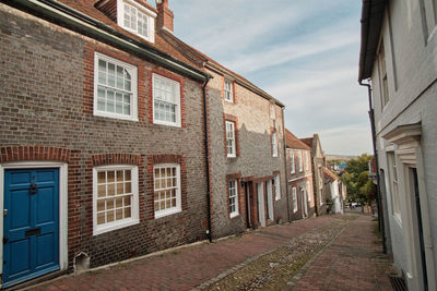 View down historic cobbled keere street with bright blue front door in foreground lewes sussex uk