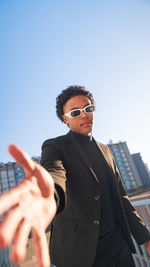 Young man wearing sunglasses while standing against sky