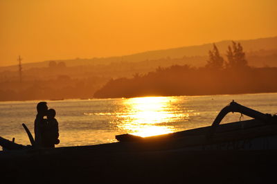 Silhouette man standing by sea against sky during sunset