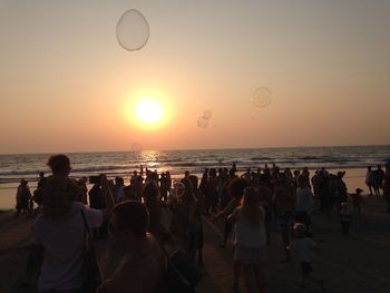 People on beach against sky during sunset