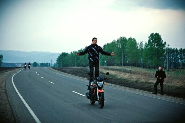 MAN RIDING MOTORCYCLE ON ROAD