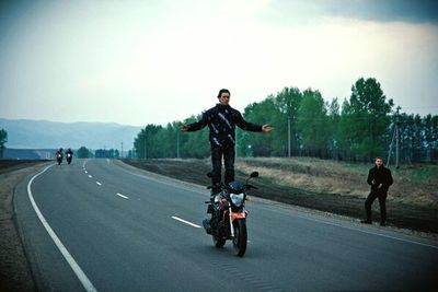 Full length of man riding motorcycle on road