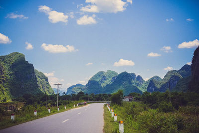 Empty road along landscape and mountains against sky