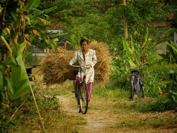 Woman with bicycle leaning on farm