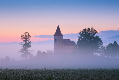 Rural gothic church in a cemetery on a foggy morning.