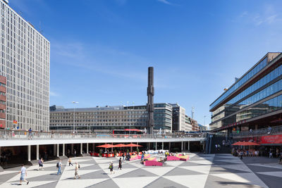 People at sergels torg against sky in city