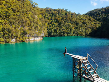 Man sitting over lake on diving platform