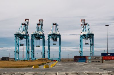 Cranes at pier against sky