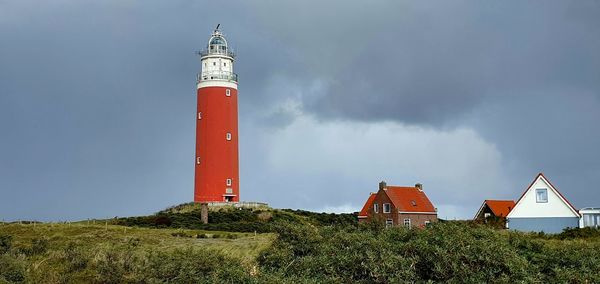 Lighthouse amidst buildings against sky