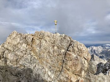 Low angle view of cross on rock against sky