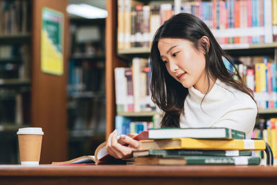 Young woman reading book on table