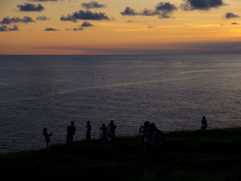 Silhouette people on beach against sky during sunset