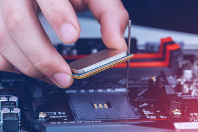 Cropped hand of man placing computer chip on mother board