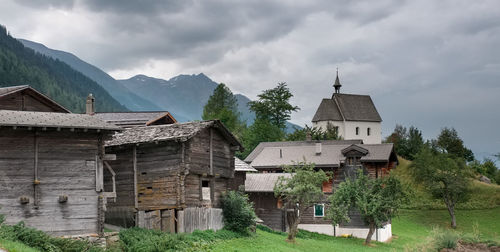 Houses on field by buildings against sky