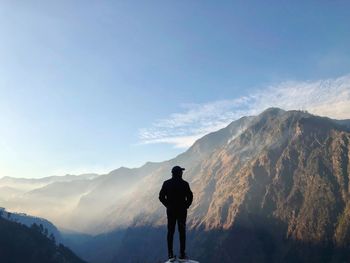 Rear view of silhouette man standing on mountain against sky