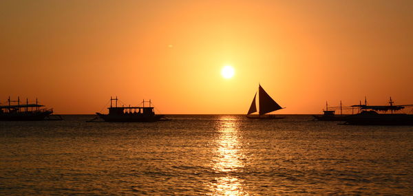 Silhouette sailboats in sea against sky during sunset