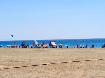 Group of people on beach against clear sky