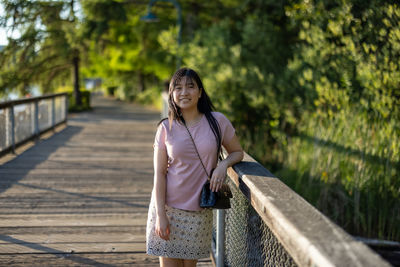 Portrait of young woman standing on footbridge