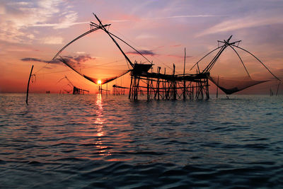 Silhouette fishing boat in sea against sky during sunset