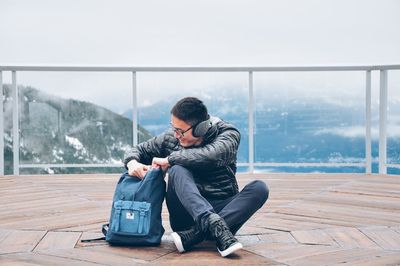 Woman sitting on snow in city against sky