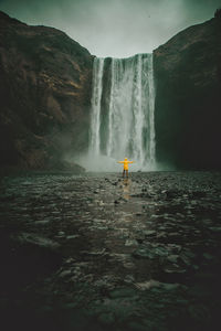 Rear view of man standing at waterfall