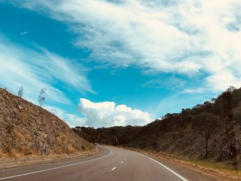 Empty road amidst plants against sky