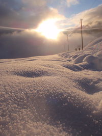 Snow covered landscape against sky during sunset