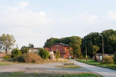 Road amidst trees and buildings against sky