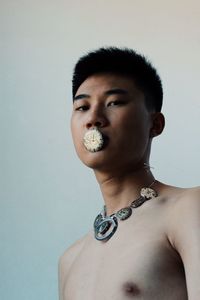 Portrait of shirtless young man against white background