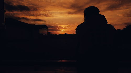 Silhouette woman standing against orange sky