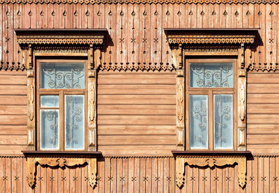 The old wooden textured facade of the house with carved platbands, curly wall elements.