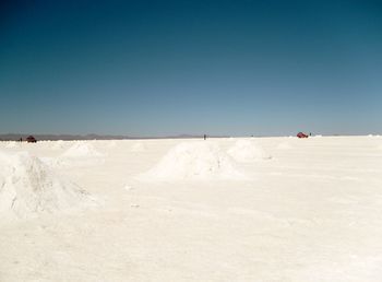 Scenic view of snowcapped field against clear blue sky