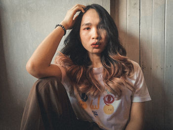 Portrait of young woman against wall