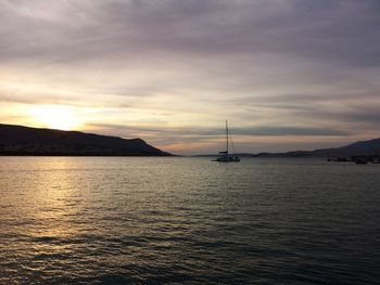 Sailboats sailing on sea against sky during sunset