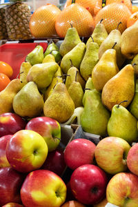 Bright background from fresh fruits. apples, pears, pineapple, pamela, persimmons are in stalls.