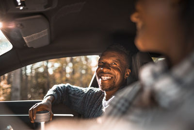 Smiling man looking at female friend in car during road trip