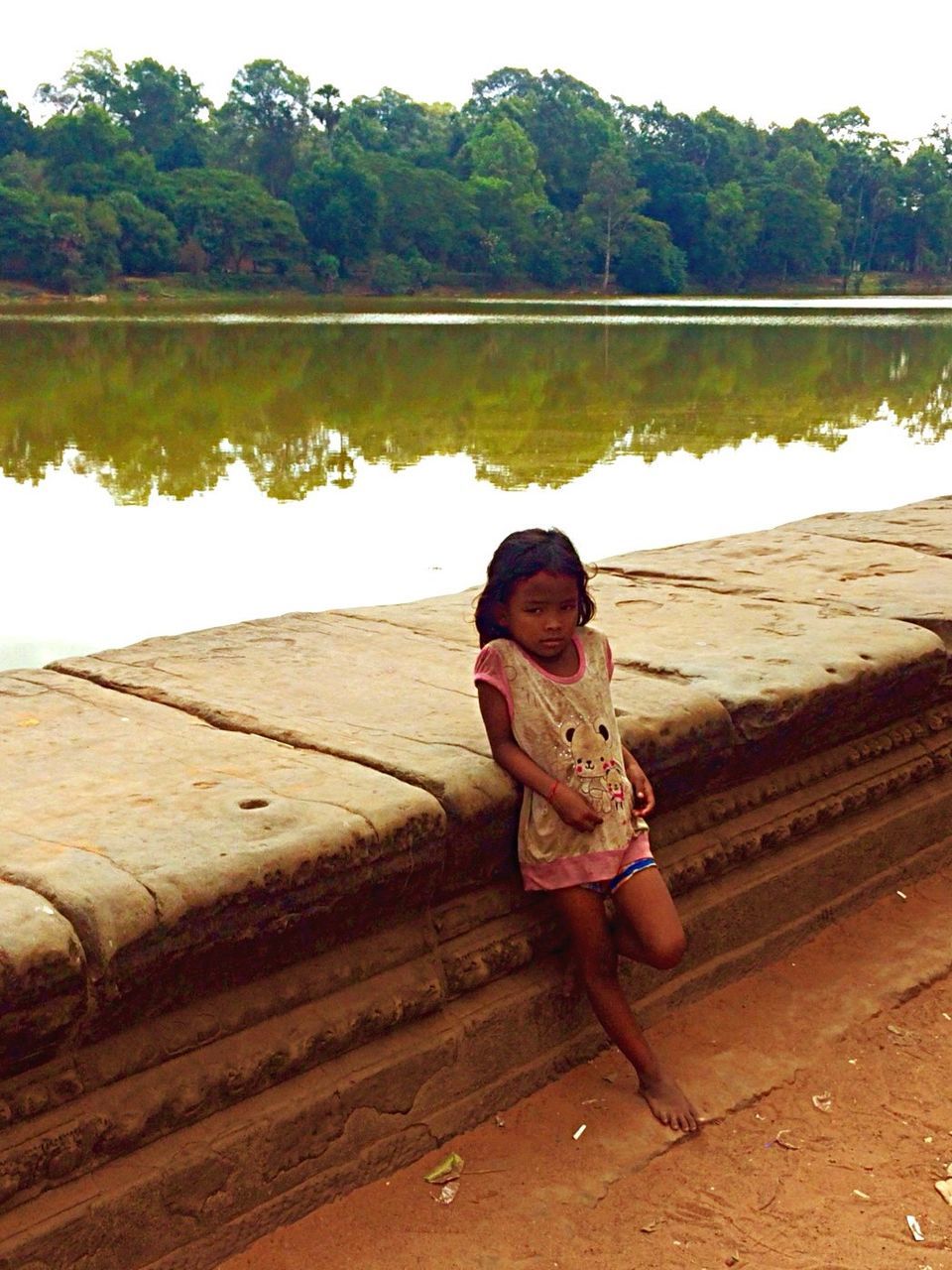 FULL LENGTH OF BOY SITTING ON LAKE AGAINST SKY