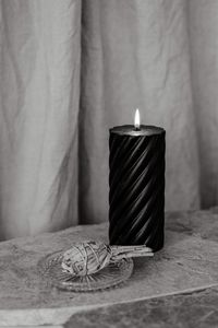 Close-up of illuminated candle on table