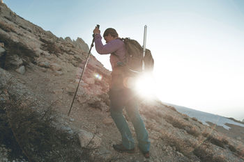 Mid adult woman hiking on mountain against sky