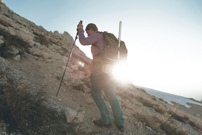 Rear view of man standing on mountain against sky