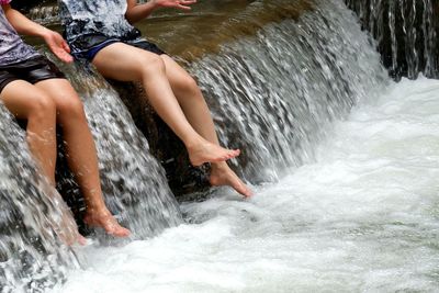 Low section of women enjoying at waterfall