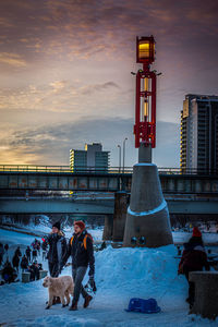 People in city against sky during sunset