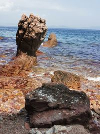 Rock formation on sea shore against sky
