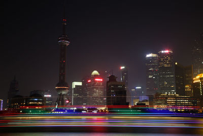 Light trails on huangpu river against illuminated city against sky